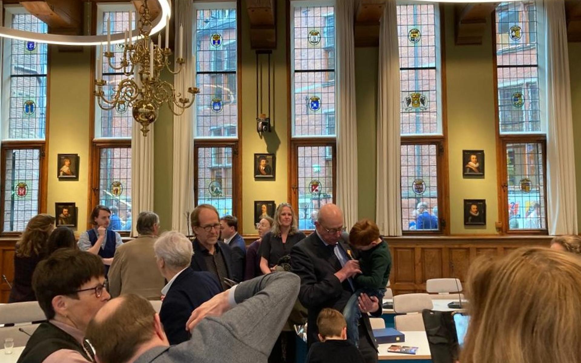 Het vers opgespelde lintje van afzwaaiende VVD-Statenlid Nico Bakker (midden) trekt de warme belangstelling van zijn kleinzoons.