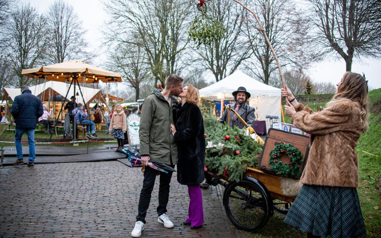 Jelmer en Amra geven elkaar een zoen onder de Mistletoe Express. De kerstmarkt in Bourtange is rustiger door de coronamaatregelen, maar bezoekers hebben het prima naar hun zin. 