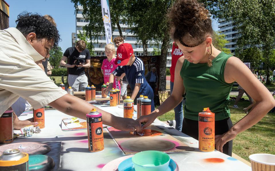 Kinderen zijn tijdens het Street Art Festival Emmerhout druk in de weer met sjablonen.