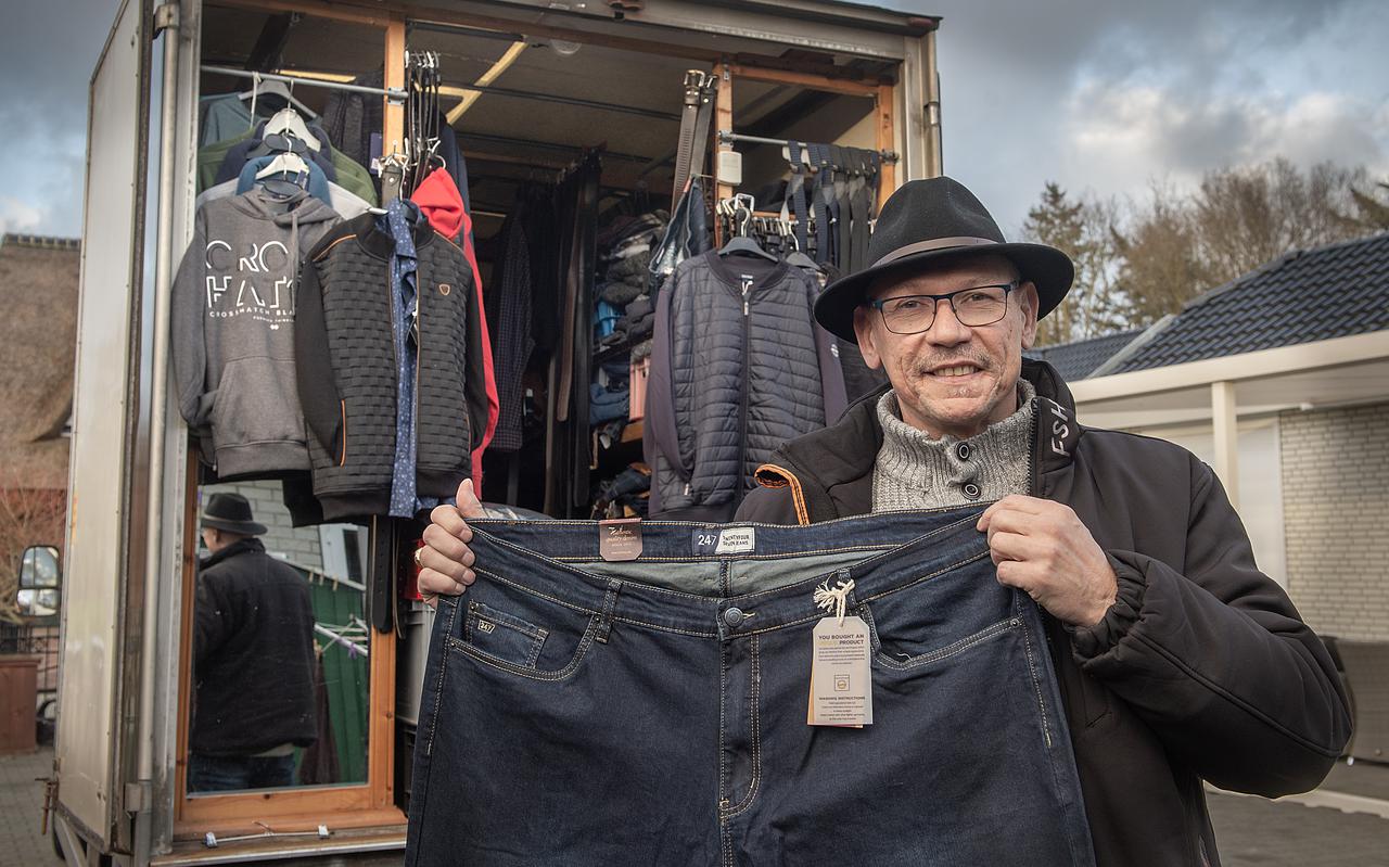 Jan Hindriks laat een spijkerbroek uit zijn rijdende kledinghandel zien.