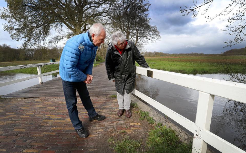 Bert Staats en Froukje Zeilemaker-Hovenkamp bekijken de herinneringsplaquette voor Johannes Hovenkamp op het witte houtwerk van de brug tussen Schipborg en Zeegse.