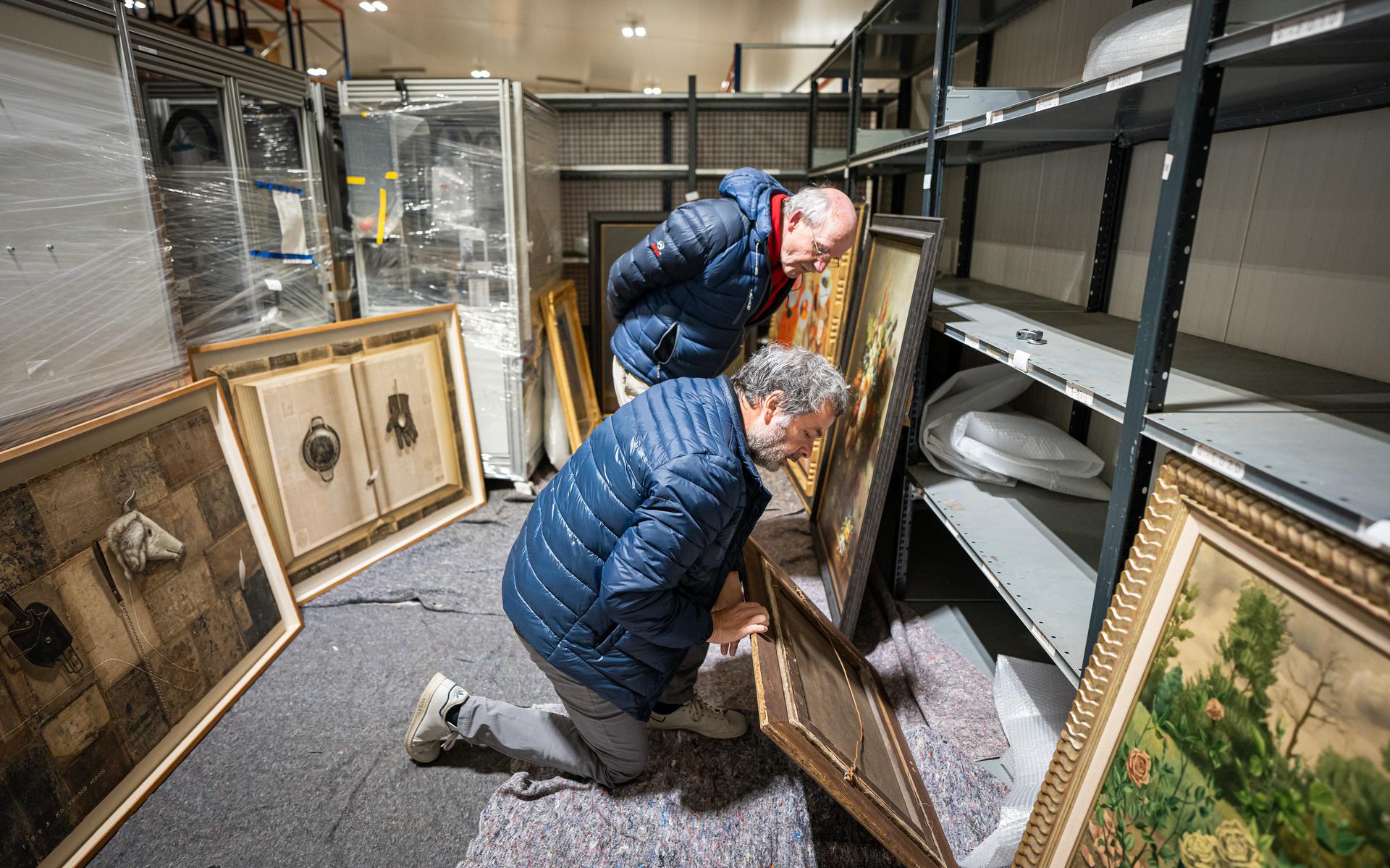 Richard ter Borg (knielend) en Willem Aanstoot inspecteren een schilderij. 