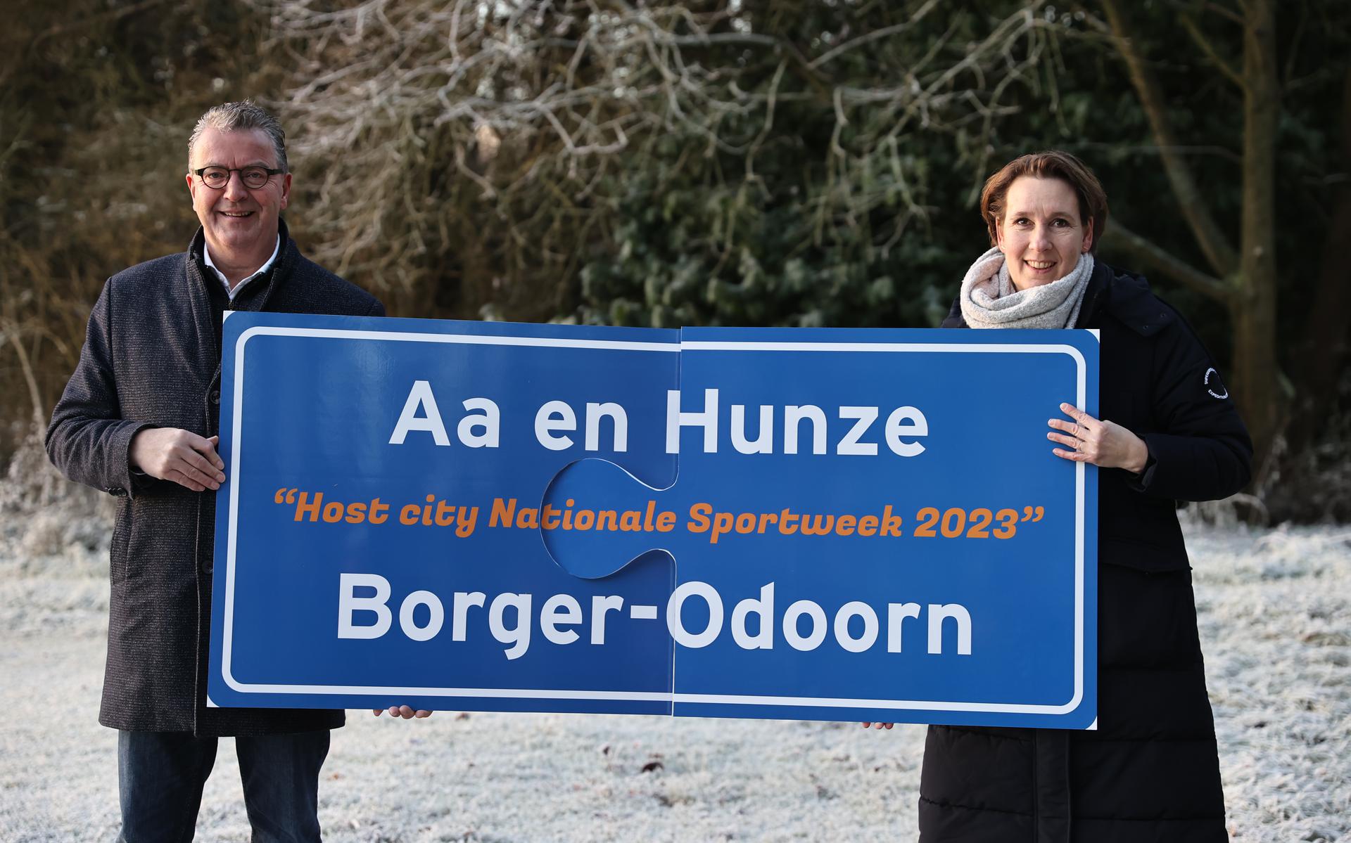 Wethouder Bas Luinge (Aa en Hunze) & wethouder Ankie Huijing (Borger – Odoorn) op de grens van beide gemeenten, namelijk in Drouwen. Het bord dat zij vasthouden staat symbool voor de samenwerking en verbinding.