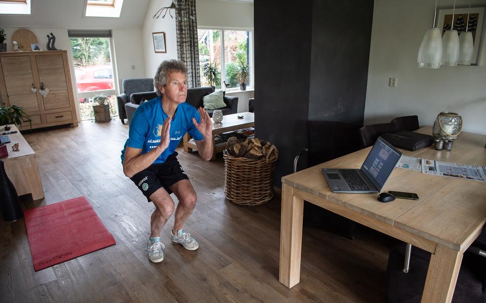 In zijn eigen woonkamer doet Gerard Meijers (60) de oefeningen die instructeur Anne Beetstra op het computerscherm voordoet.  
