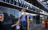 Na haar aankomst uit Mallorca verlaat studente Anna, met mondkapje, de aankomsthal van Groningen Airport Eelde.
