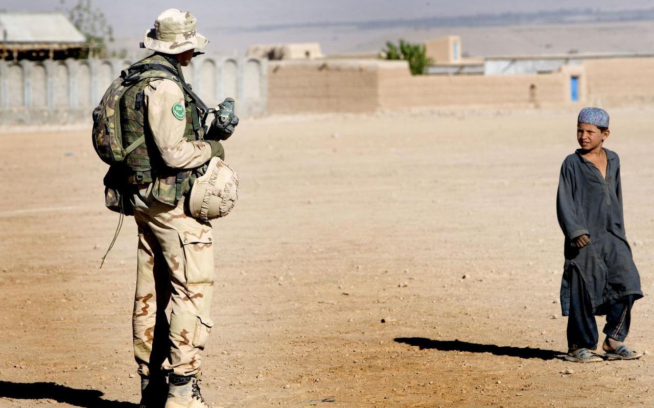 Een Afghaans jongentje kijkt naar een Nederlandse militair die
patrouilleert in Tarin Kowt.