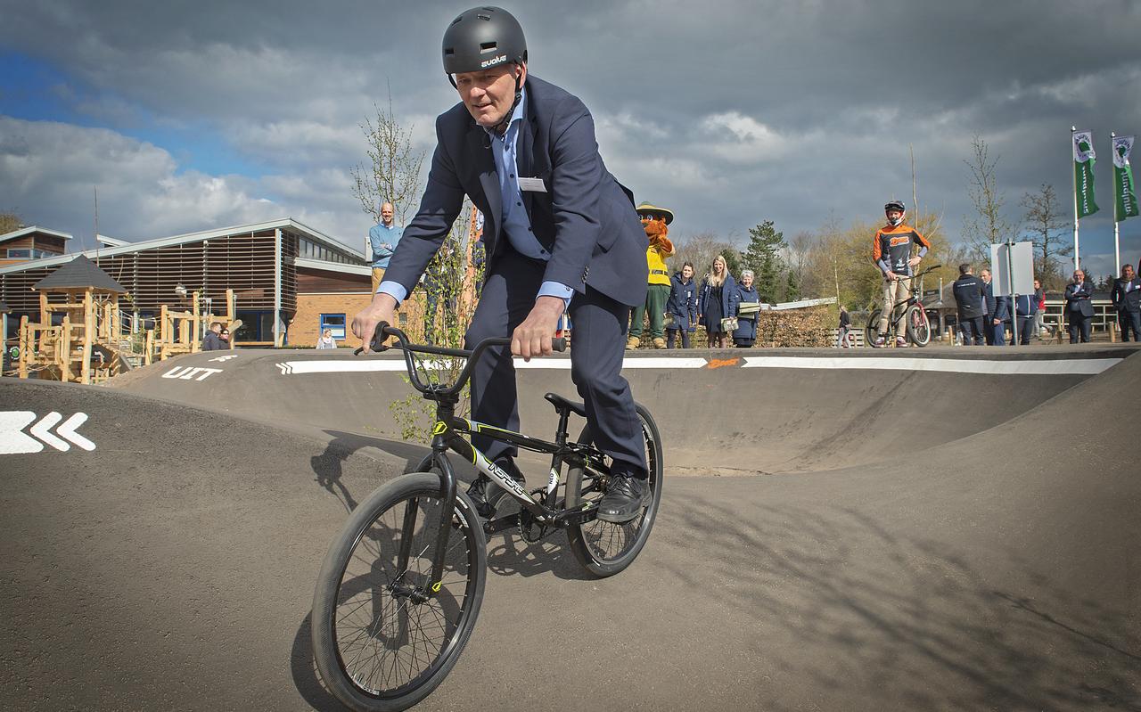 Gedeputeerde Henk Brink in pak op de kleine fiets Gedeputeerde Henk Brink in pak op de kleine fiets
