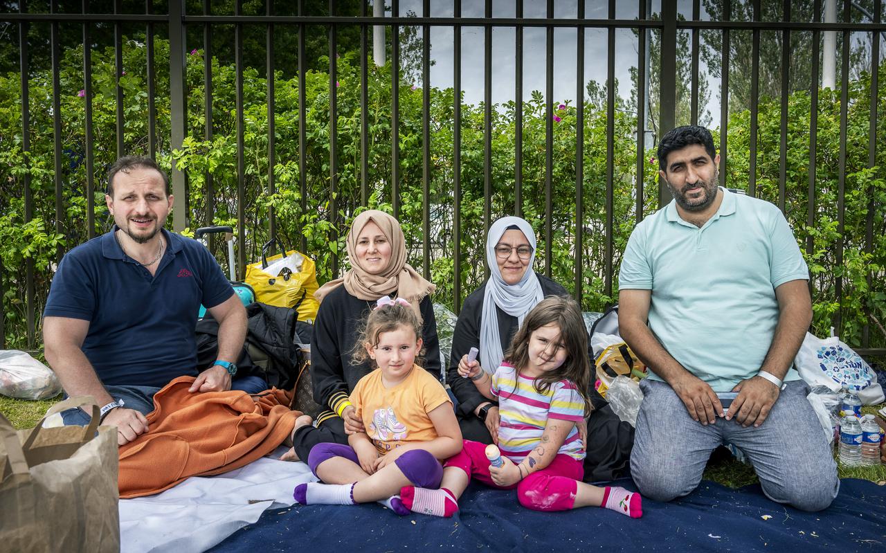 Fatih (rechts) met naast zich zijn vrouw Husniwi en dochter Ahsen. Met een bevriend geraakt gezin wachten ze in het gras van Ter Apel op een slaapplek.