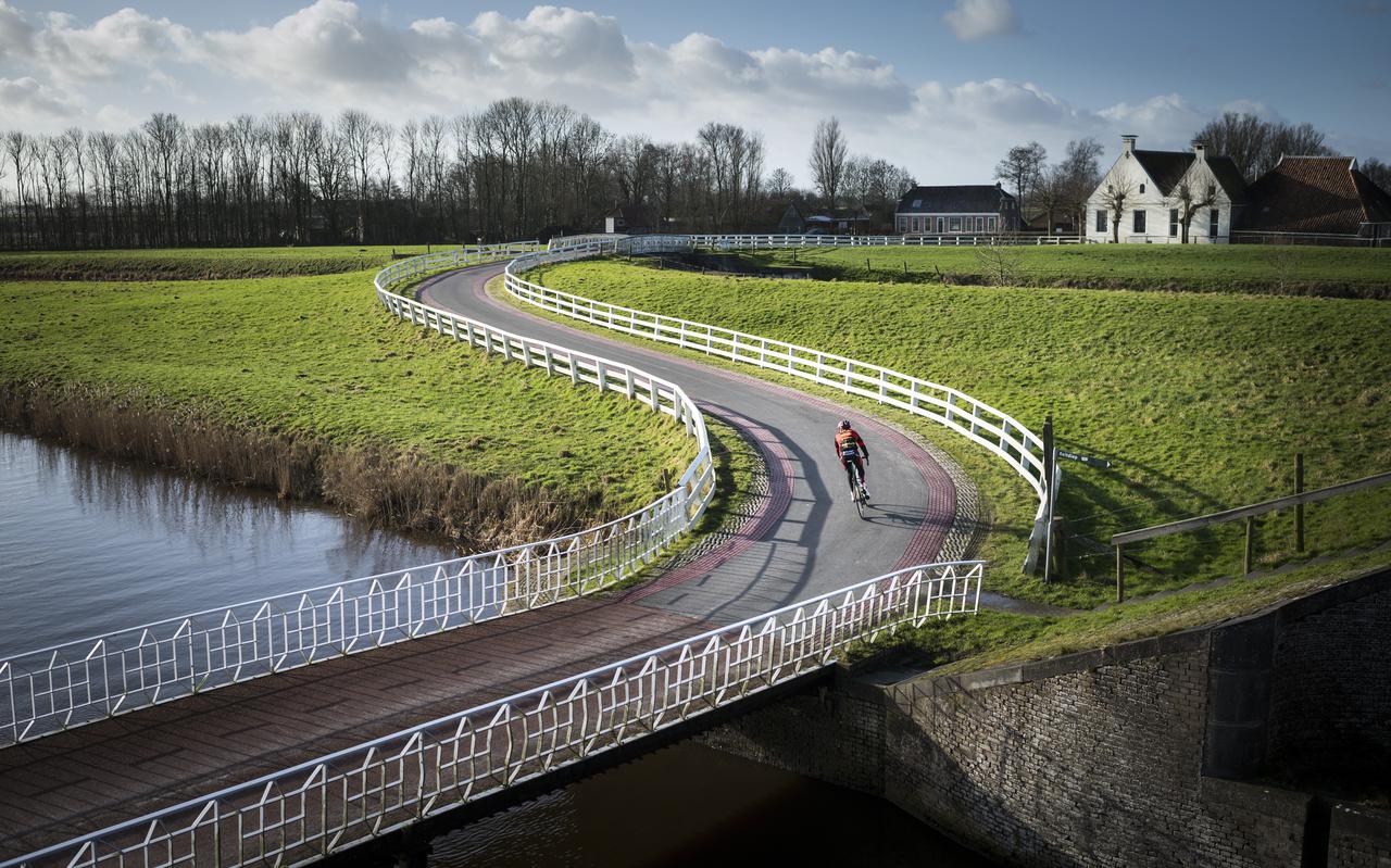  Een wielrenner rijdt door het dorpje Aduarderzijl.