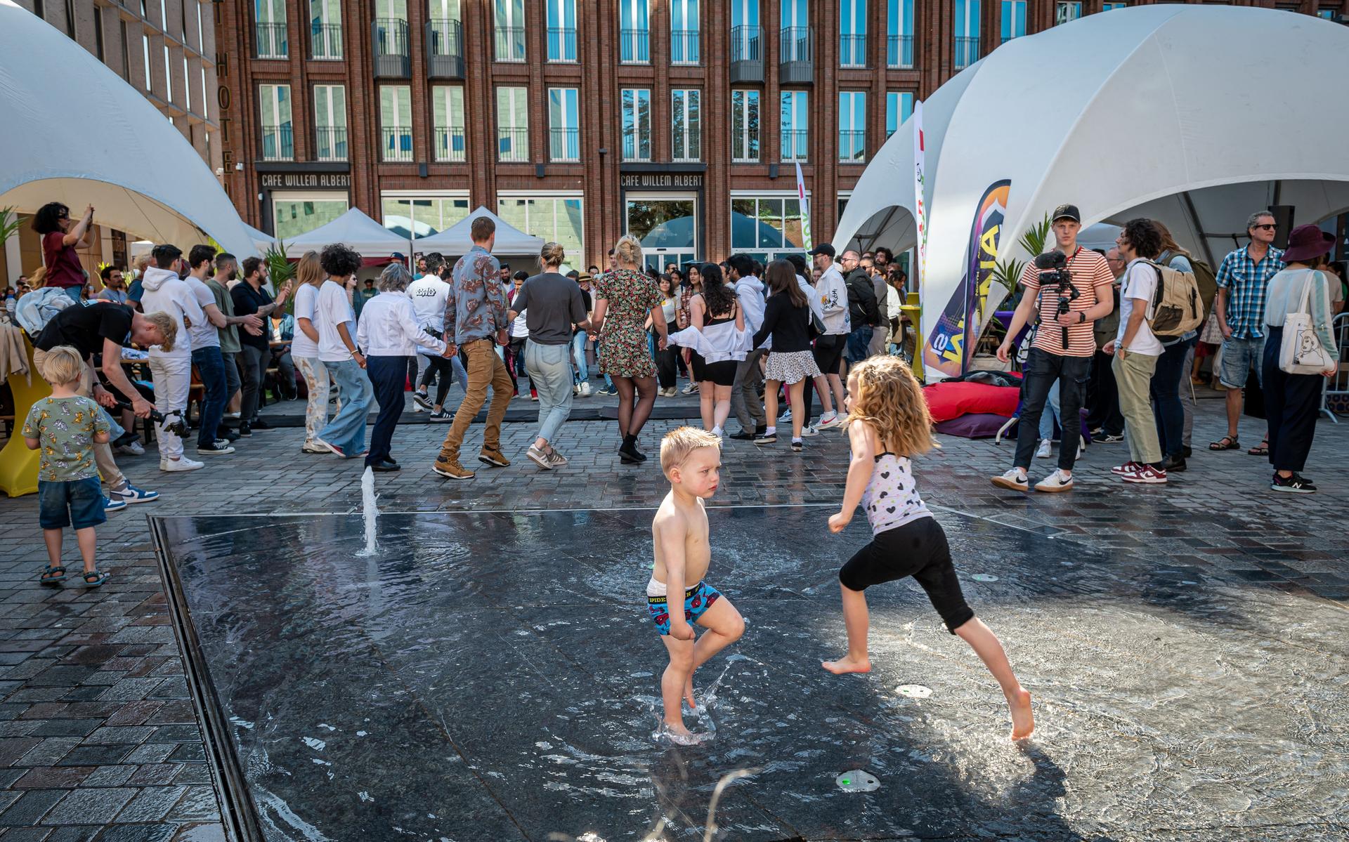 Kinderen spelen terwijl volwassenen de dabke, een Arabische volksdans, onder de knie proberen te krijgen en zich tegoed doen aan de internationale gerechtjes op de Nieuwe Markt in Groningen.