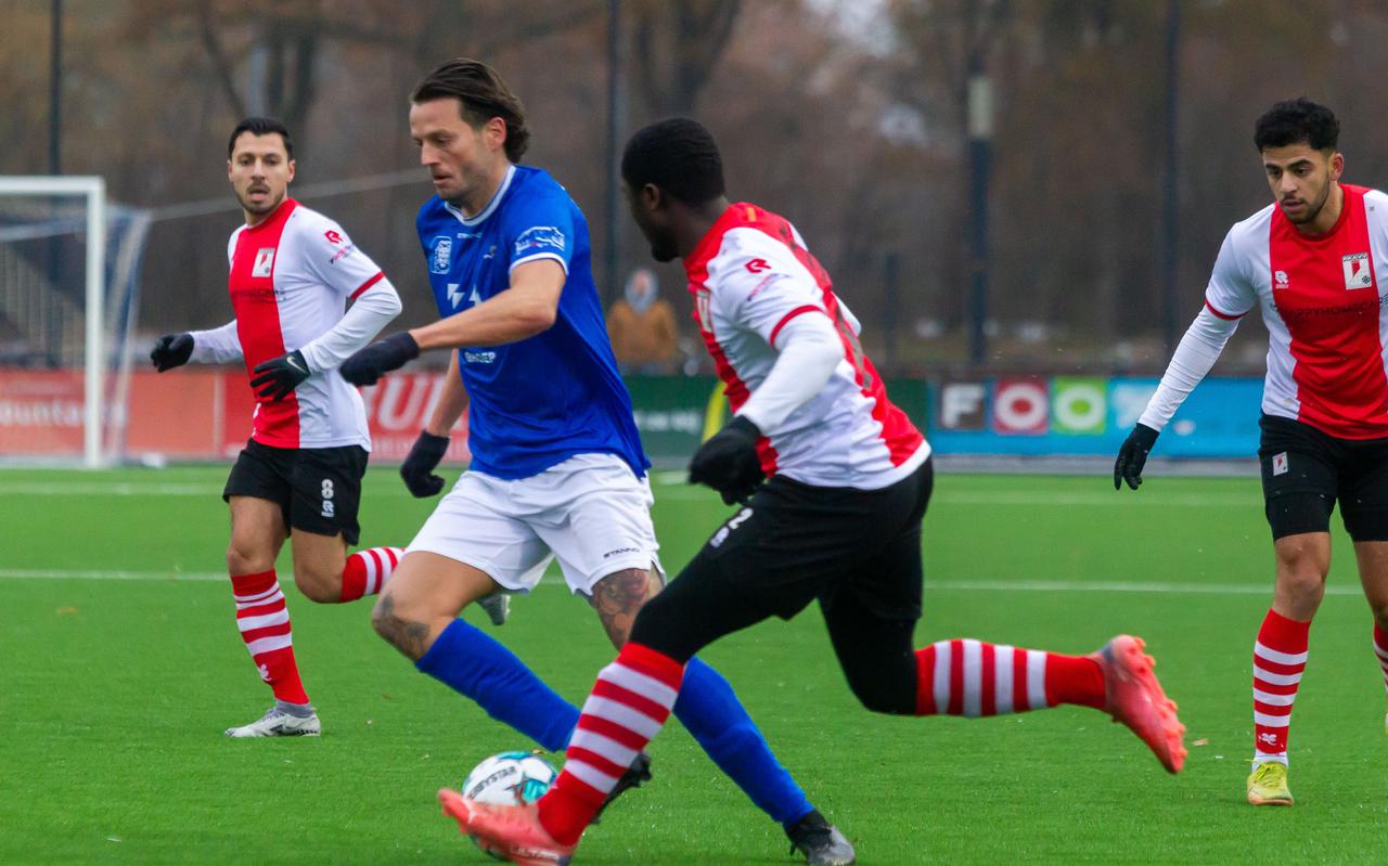 Hoogeveens doelpuntenmaker Justin Benjamins (in het blauw) wordt op de huid gezeten door de verdediging van RKAVV