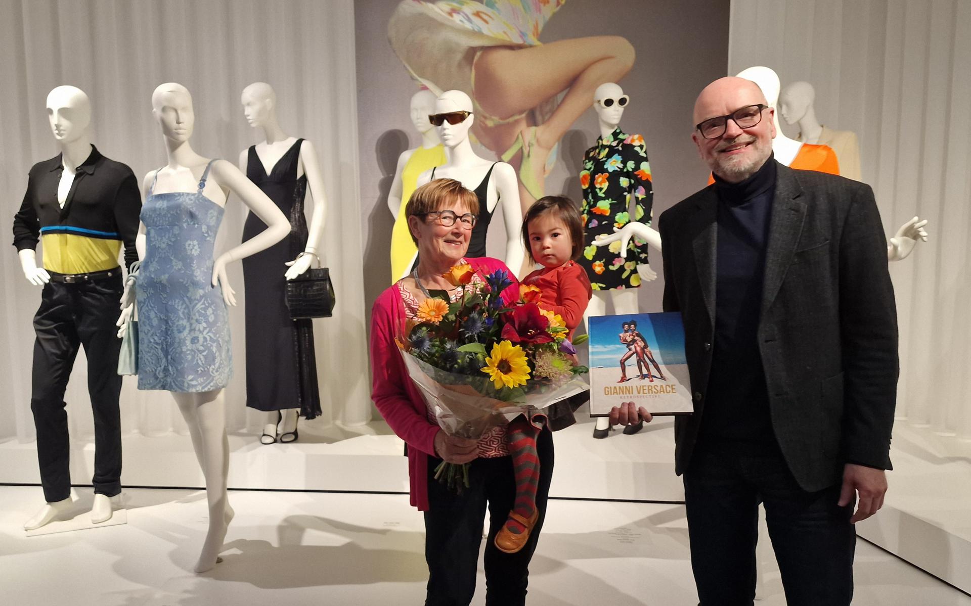 Bloemen van museumdirecteur Andreas Blühm voor Lineke Strating-Everts en haar kleindochter Sara-Yin. Lineke en Sara-Yin zijn de honderduizendste bezoeker van de tentoonstelling over Gianni Versace.