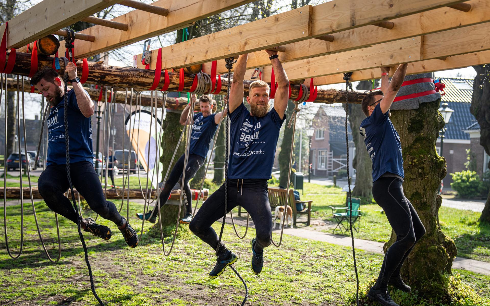 Deelnemers aan de Survivalrun Norg klauteren over de Kerkbrink.
