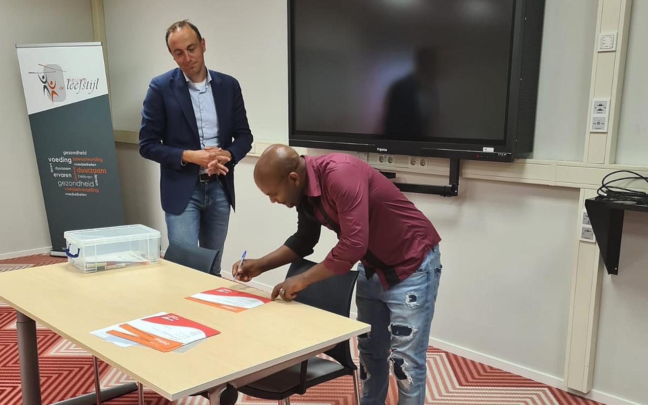 Idris Salih Ibrahim uit Eritrea ondertekent zijn certificaat van de arbeidsmarkttraining van Vluchtelingenwerk Noord-Nederland. Hij werkt nu als dakdekker. Links wethouder Jeroen Westendorp. Idris Salih Ibrahim uit Eritrea ondertekent zijn certificaat van de arbeidsmarkttraining van Vluchtelingenwerk Noord-Nederland. Hij werkt nu als dakdekker. Links wethouder Jeroen Westendorp.