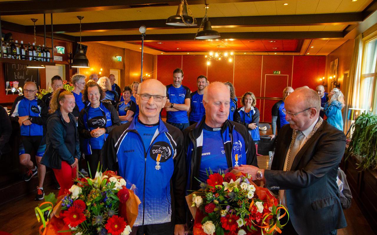 Burgemeester Klaas Smid speldt Jan de Jong (links) en Harry Kuipers de onderscheidingen op tijdens een reünie van de loopgroep in Peize.