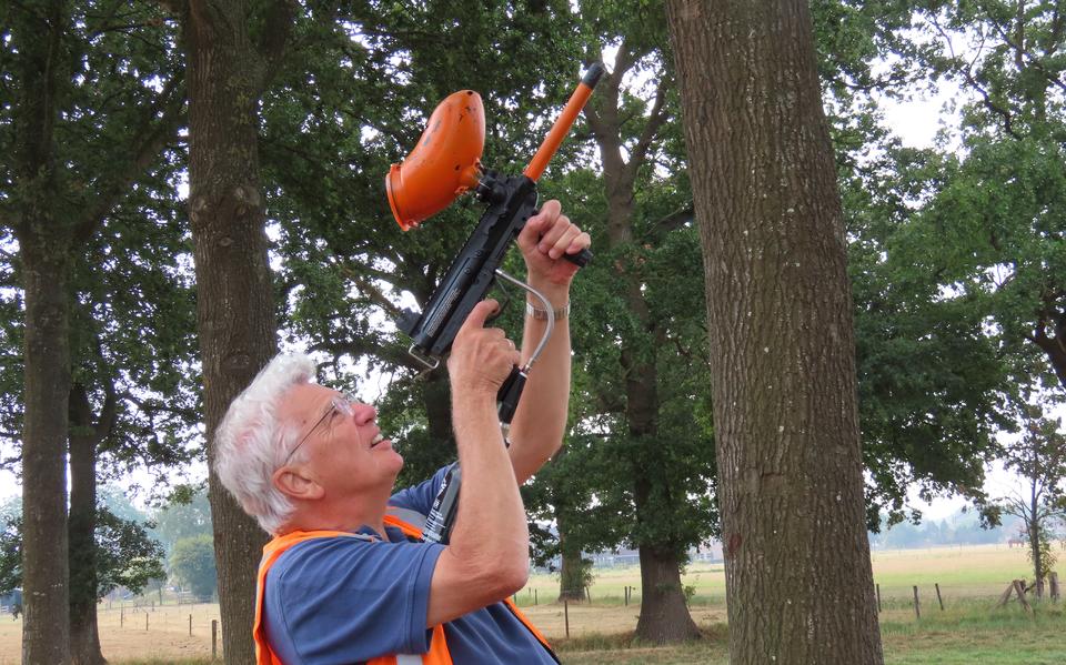 Guus Hellingman (man van Silvia Hellingman) met een paintballgeweer waarin hij de feromonen in de boom schiet.