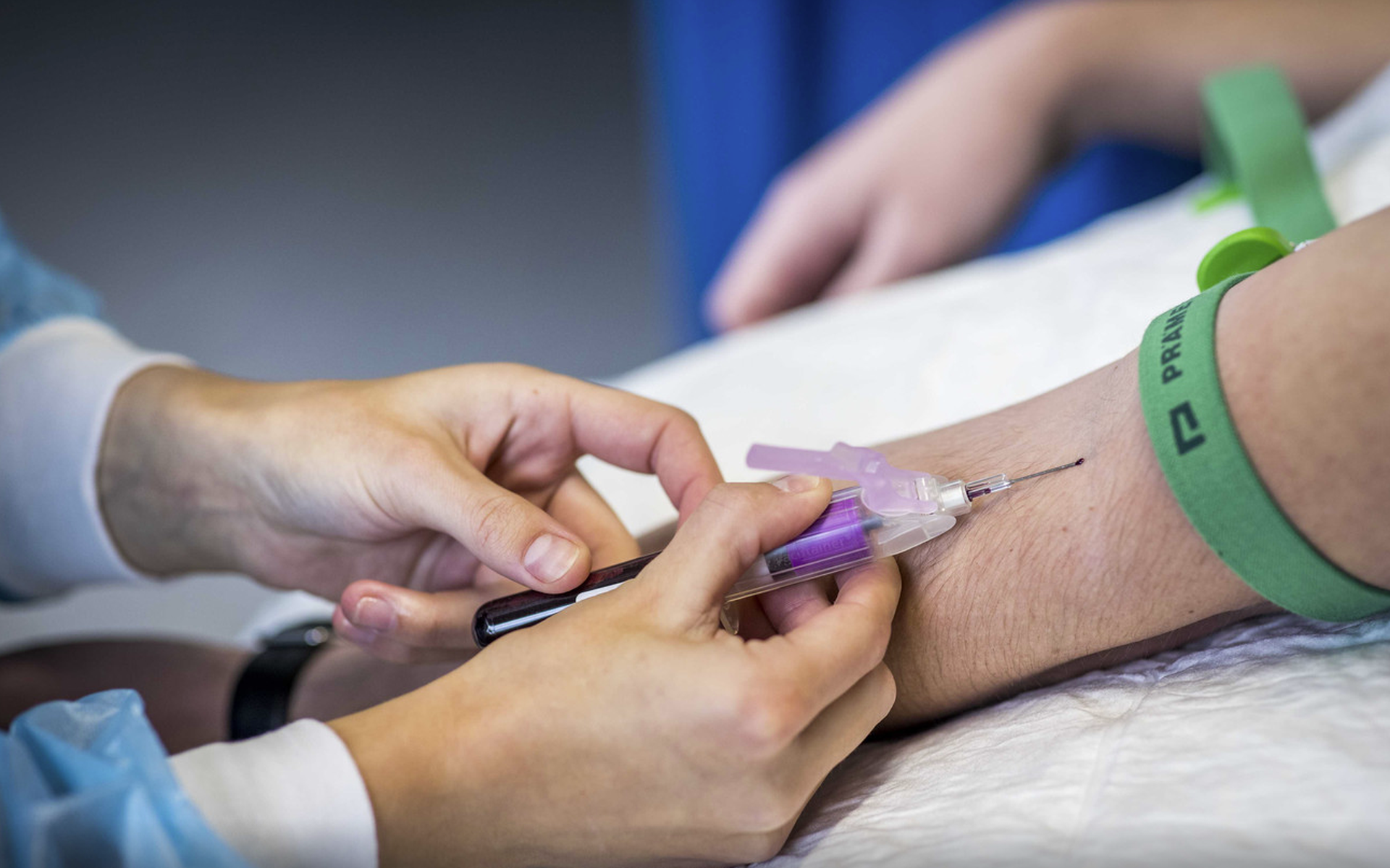 Een medewerker van de GGD in Limburg prikt bloed bij een deelnemer om te testen op antistoffen tegen het coronavirus.