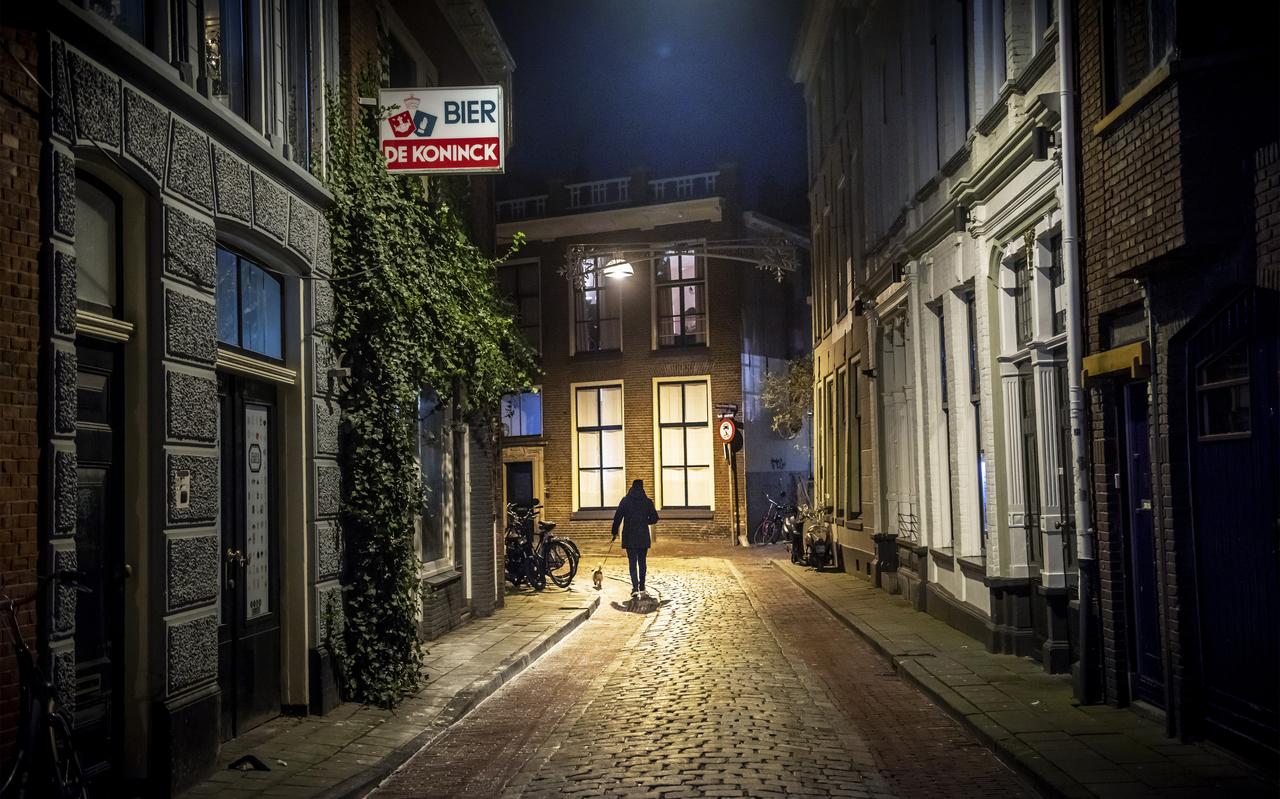 Een eenzame wandelaar met een hondje in de Kromme Elleboog in Groningen. Hij is een van de weinigen die na 21.00 op straat is. Een eenzame wandelaar met een hondje in de Kromme Elleboog in Groningen. Hij is een van de weinigen die na 21.00 op straat is.