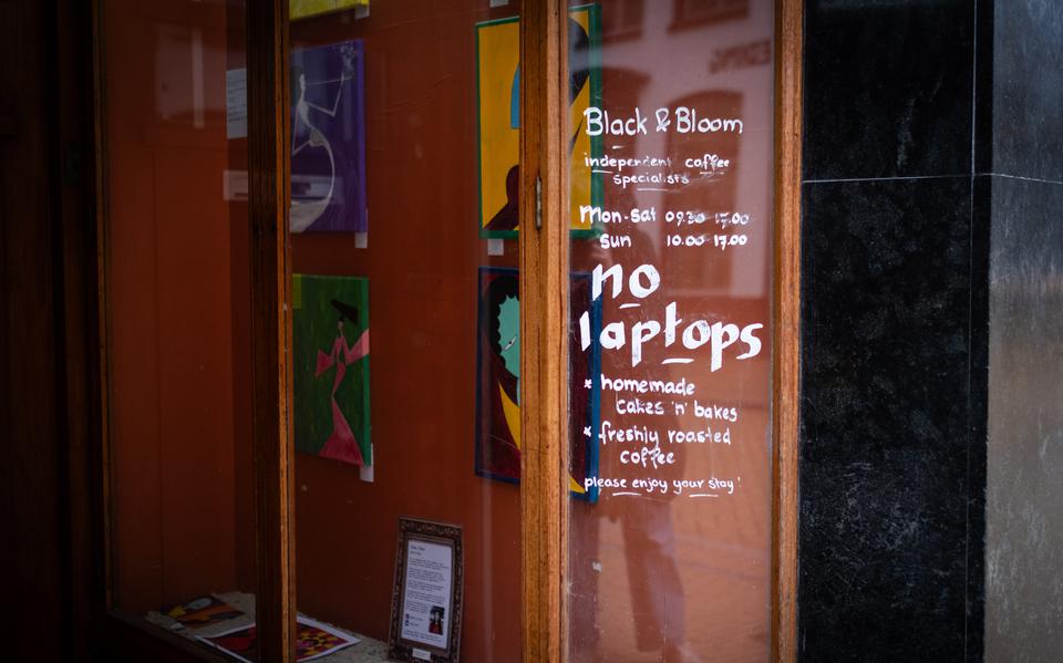 Op het raam van Black & Bloom is de boodschap luid en duidelijk: geen laptops.