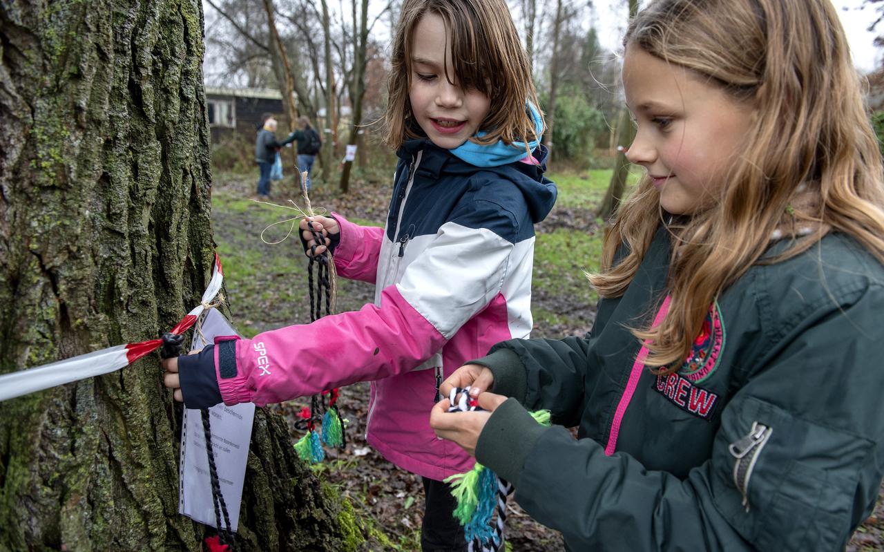 Silke Bezema (voorgrond) en Emma Stroebe, beiden 9 jaar, hangen een briefje met een waarschuwing aan een boom op recreatiepark Meerzicht: laat mij staan!           