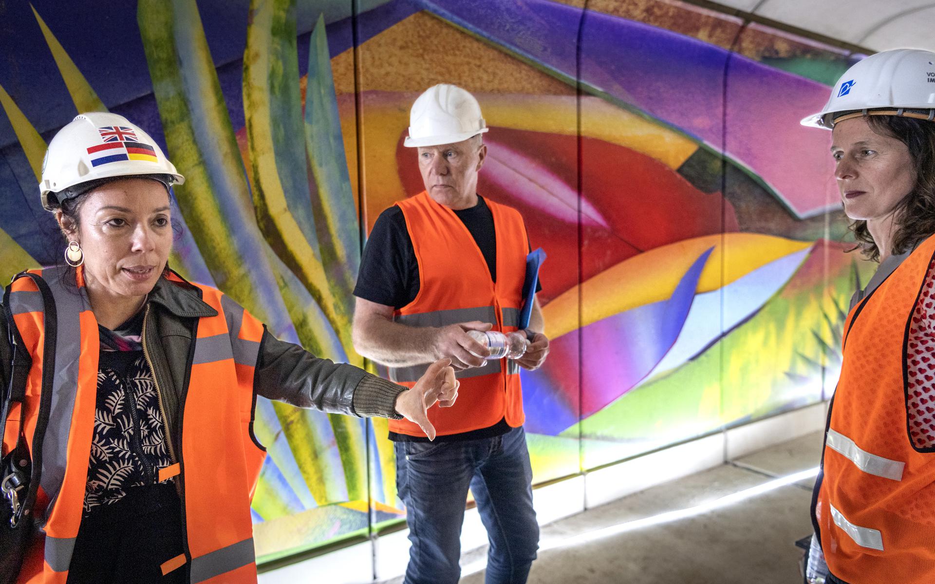 Kunstenares Hadassa Emmerich (links) laat haar gigantische muurschildering op folie afdrukken door Egbert Ipema van SignUp. Samen met Nicoline Wijnja van Kunstpunt bekijken ze het eerste deel in de fietstunnel bij openluchtbad De Papiermolen. 