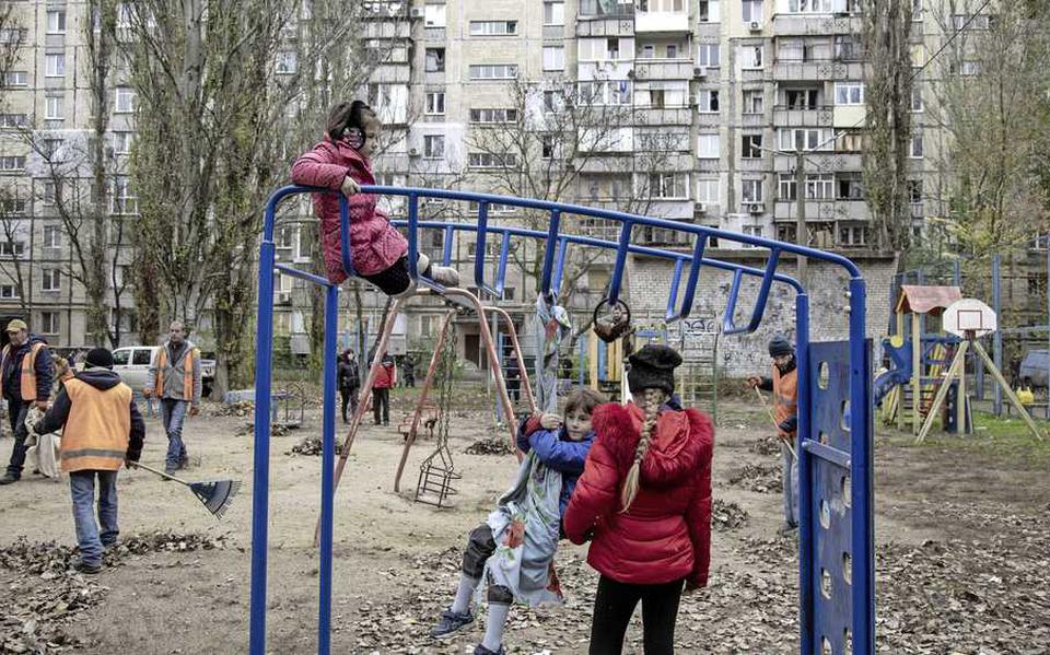 Kinderen aan het spelen vlakbij een door Russen beschadigd gebouw, in de Oekraïense stad Mykolaiv.