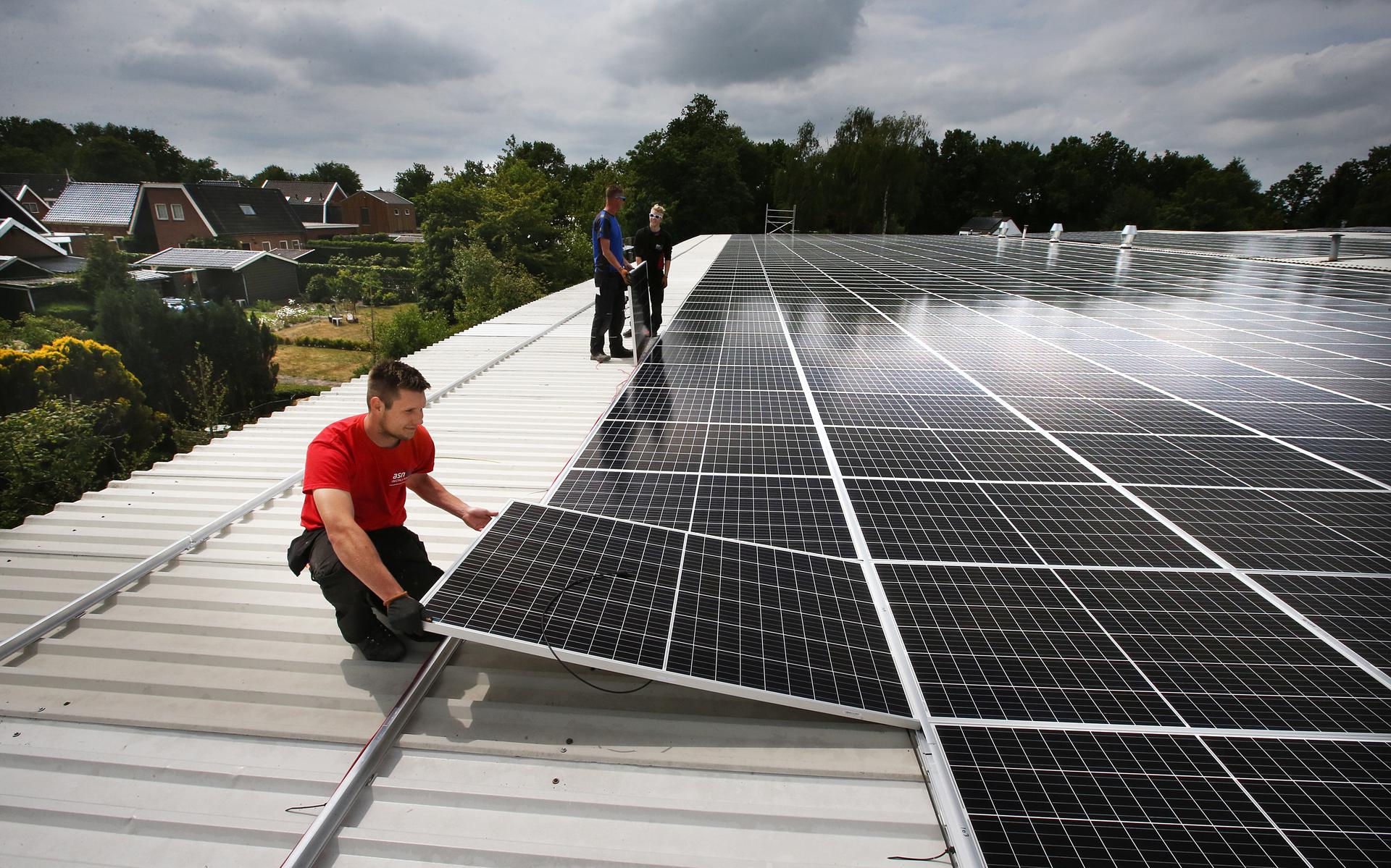 Monteurs installeren zonnepanelen op het dak van een loods. 
