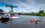 De Swim Challenge passeert Garnwerd, ze zijn ongeveer halverwege de 35 kilometer lange route. Vanaf de brug en kade worden ze aangemoedigd. Aan het eind van de estafettetocht hebben de zwemmers 217.000 euro opgehaald.