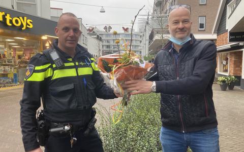Jan van Peer (rechts) ontvangt van wijkagent van Tinus Berghuis een bos bloemen. Dankzij Van Peer kon een telefoonrover worden aangehouden. 
