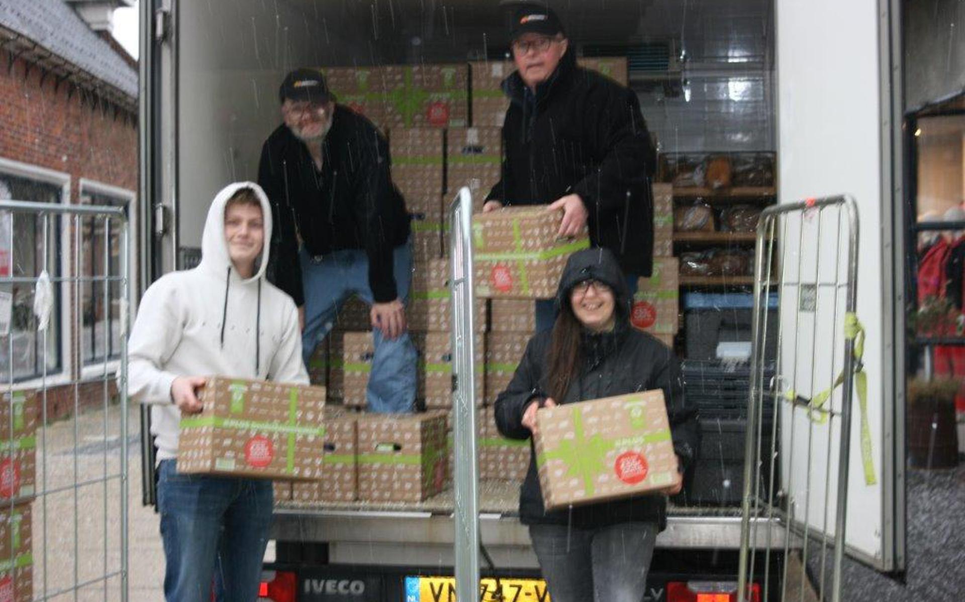 Medewerkers van een PLUS-winkel en de voedselbank zijn de dozen tijdens een fikse hagelbui aan het inladen. Eigen foto
