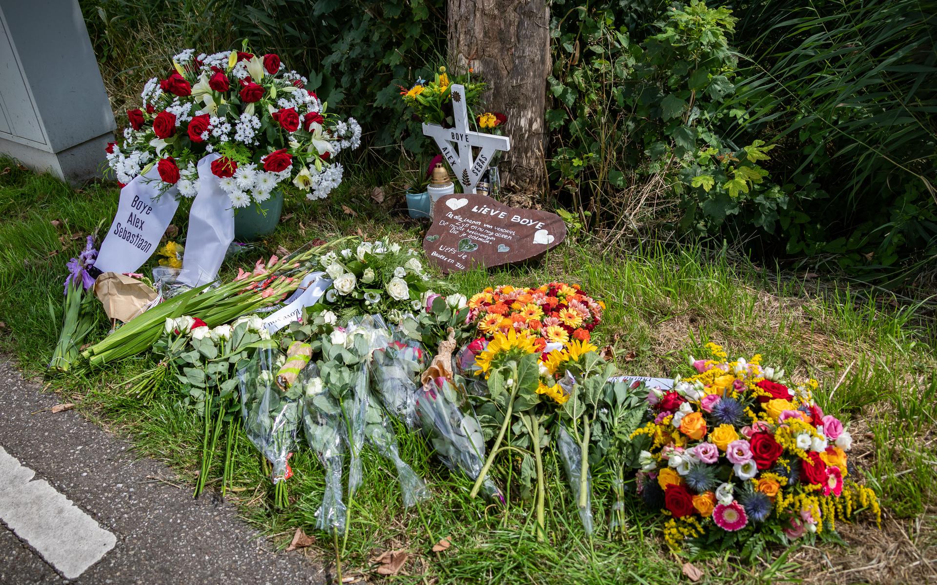Bloemen, een kruis en een gedenksteen bij de plek des onheils. 