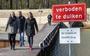 Coriene Stokhof en Daniëlle Veenstra (zwarte jas) lopen over de herstelde brug in Natuurbad Zandpol die naar hen is genoemd.  
Achter hen bestuurslid Albert Schimmel.