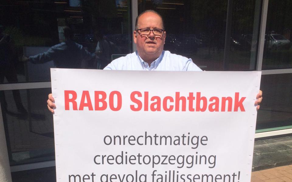 Henk Oosterhof protesteert met spandoek bij de Rabobank in Stadskanaal.