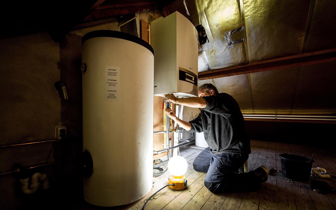 Een installateur is bezig met de installatie van een warmtepomp bij een verwarmingsketel, als onderdeel van een project om een jaren zestigwoning energiezuinig te maken. Veel installateurs hebben het nu zo druk dat ze regelmatig nee moeten verkopen.