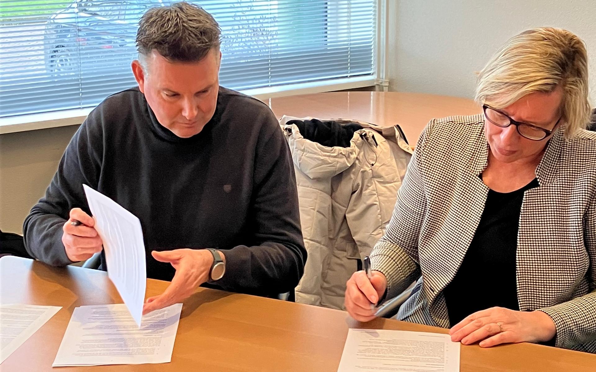 Harry Oosting, directeur bestuurder van woningstichting Goud Wonen en wethouder Mariette de Visser zetten een handtekening onder de eerste projectovereenkomst. Foto: Gemeente Het Hogeland