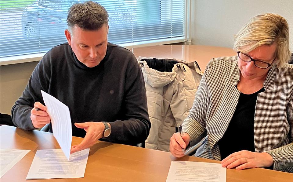 Harry Oosting, directeur bestuurder van woningstichting Goud Wonen en wethouder Mariette de Visser zetten een handtekening onder de eerste projectovereenkomst. Foto: Gemeente Het Hogeland