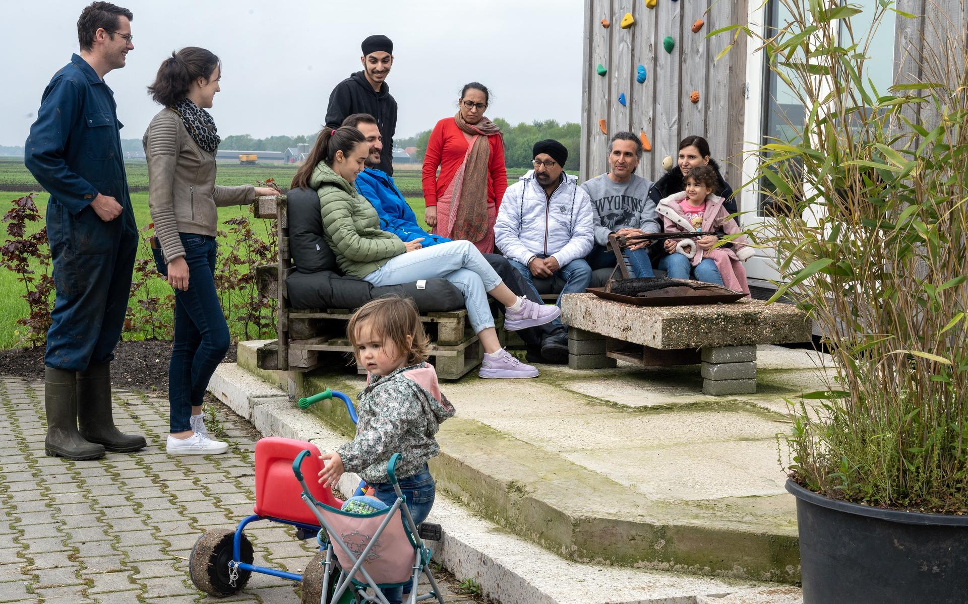 Bij een van de huisjes op het erf van melkveehouder Bom. Van links naar rechts: Herbert en Laura Bom met op de voorgrond dochtertje Maud, Pariya en Hossein uit Iran, Kamal, Taran en Autar uit Afghanistan en Mohammad en Afarin met dochtertje Taranj (3).