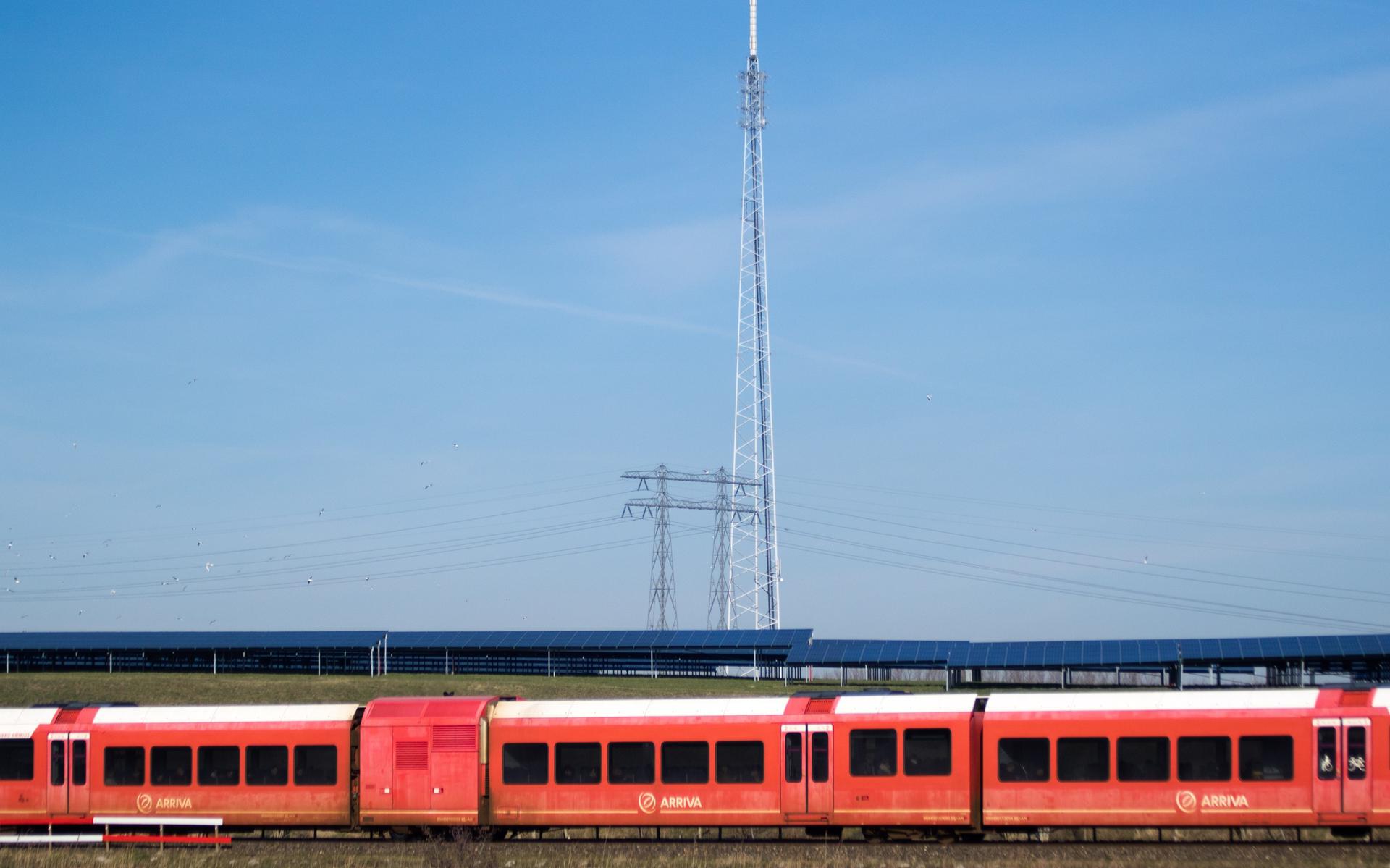 Een trein van Arriva passeert zonnepark Woldjerspoor in Groningen. 