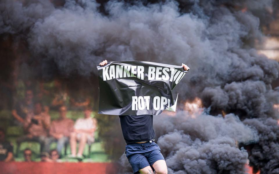 Een hooligan stormt het veld op met een spandoek tijdens FC Groningen-Ajax.