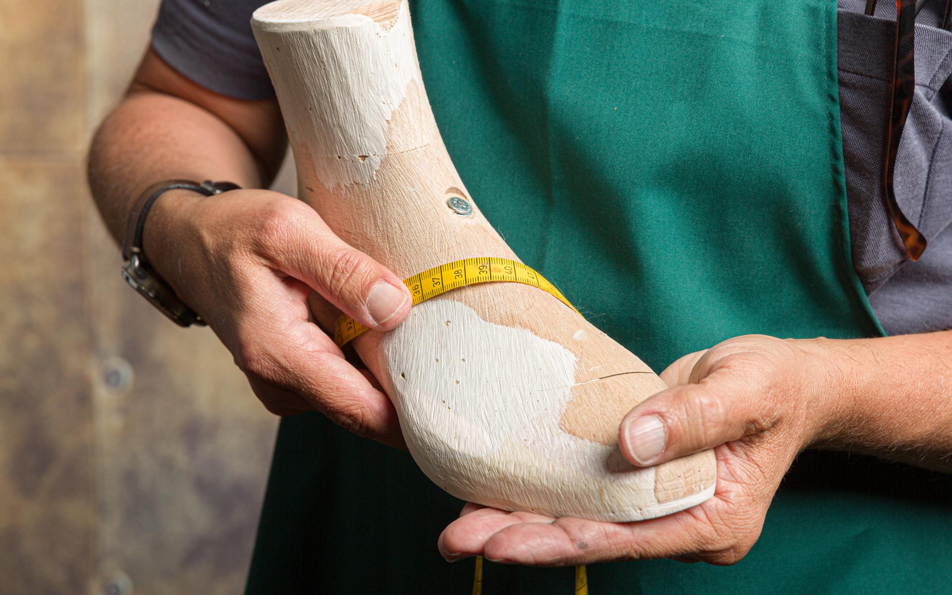 Orthopedisch schoenmaker die de kwaliteit van een houten leest controleert met behulp van een meetlint