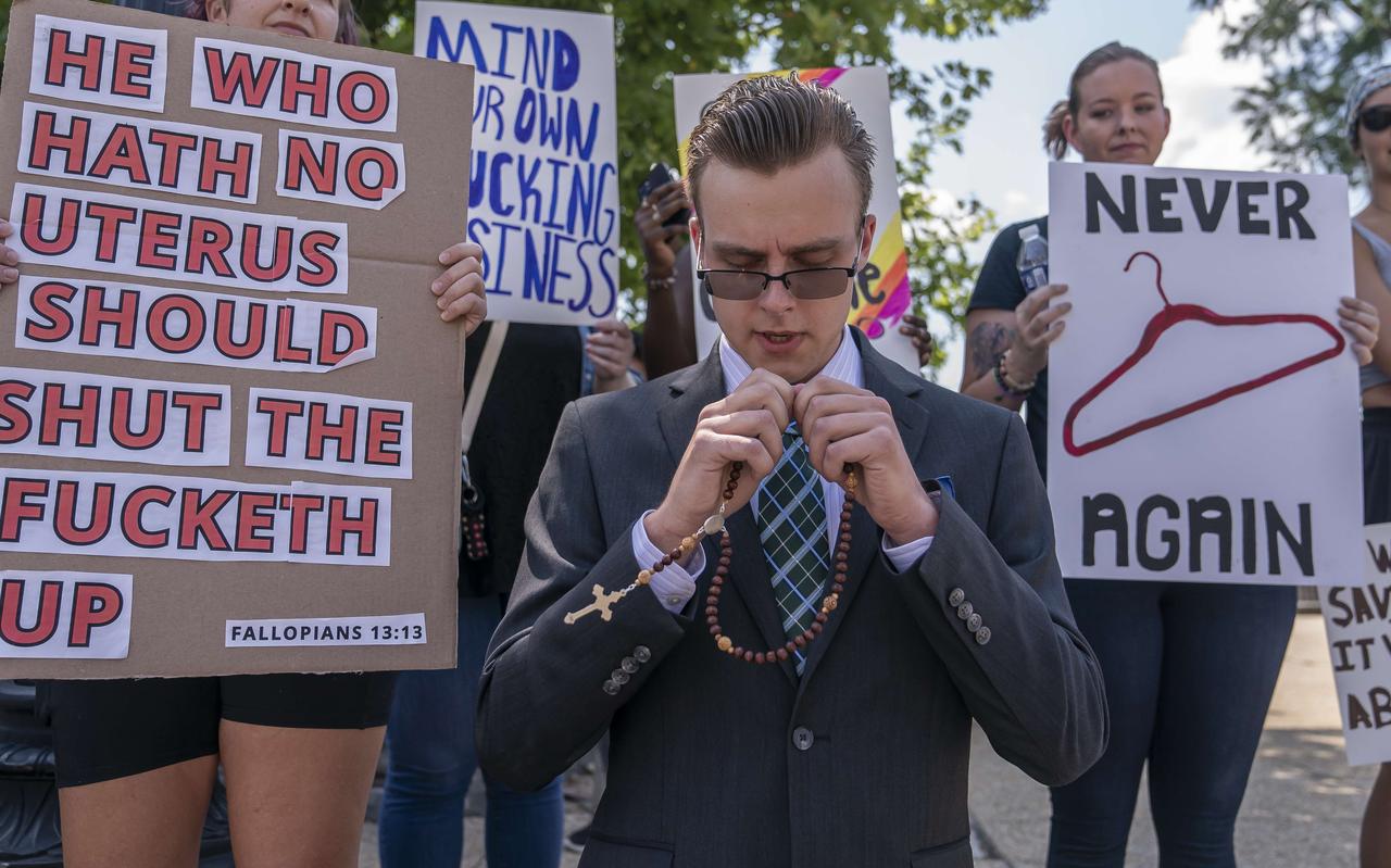 Een demonstrant tegen abortus zit knielend te bidden in Washington DC, omgeven door voorstanders van abortus. Foto: Nathan Howard/Getty Images/AFP Een demonstrant tegen abortus zit knielend te bidden in Washington DC, omgeven door voorstanders van abortus. Foto: Nathan Howard/Getty Images/AFP