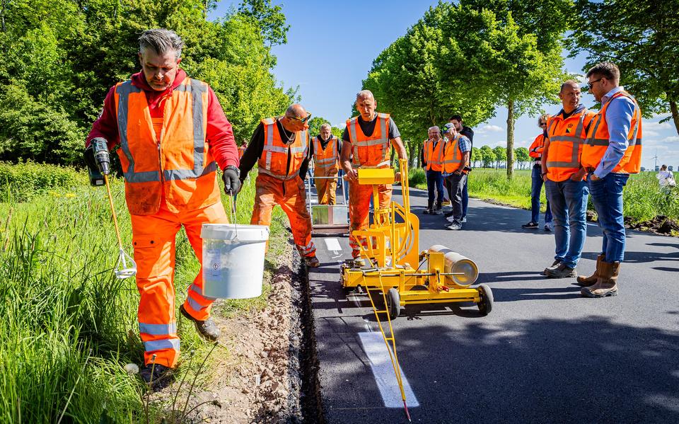 Sietze Schapelhouman brengt nog handmatig het nieuwe , milieuvriendelijke lijmarkering product aan. Het asfalt op de Hoofdweg in Nieuw Beerta had de wereldprimeur.  