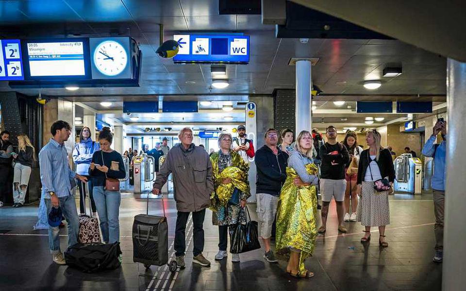Reizigers wachten op een trein op station Amsterdam Centraal.