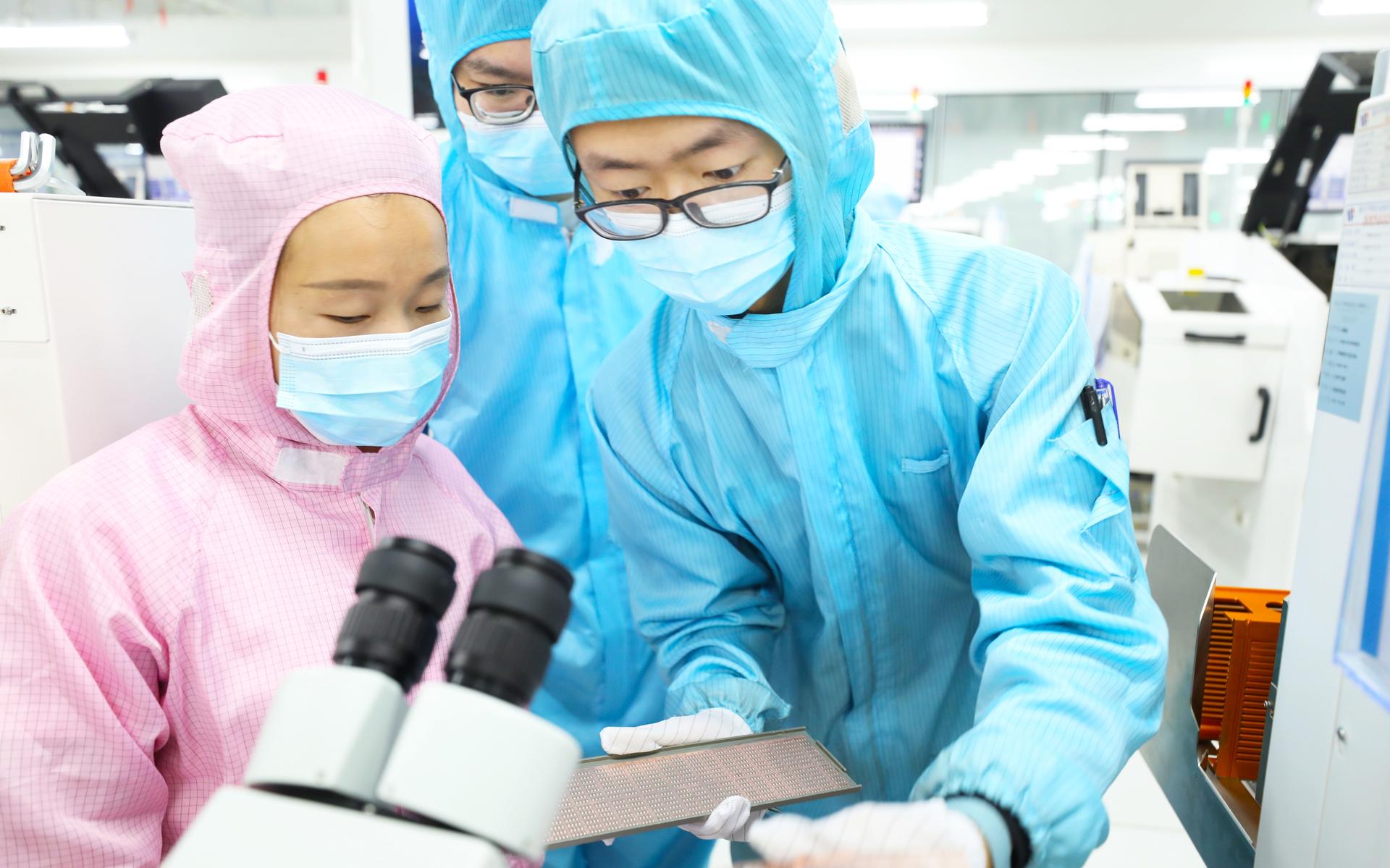 Medewerkers van een Chinese computerchipfabriek bekijken de chips die ze hebben gemaakt.