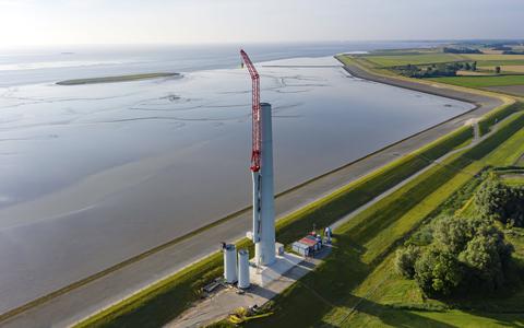 Een speciale kraan bouwt de windmolens op de Oostpolderdijk bij Spijk. 