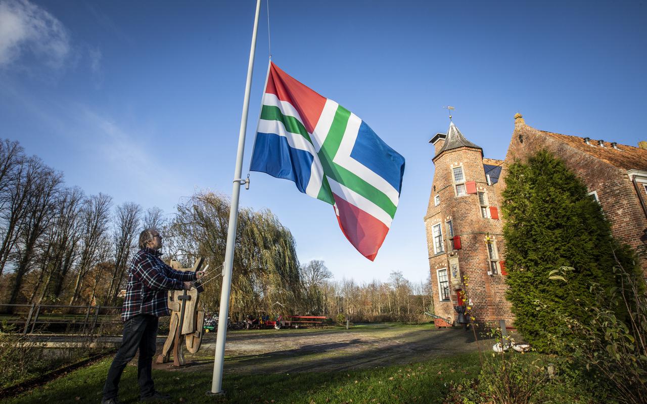 Piet van Geffen van de Dorpsraad Wedde hangt bij de Burcht in Wedde de vlag halfstok.