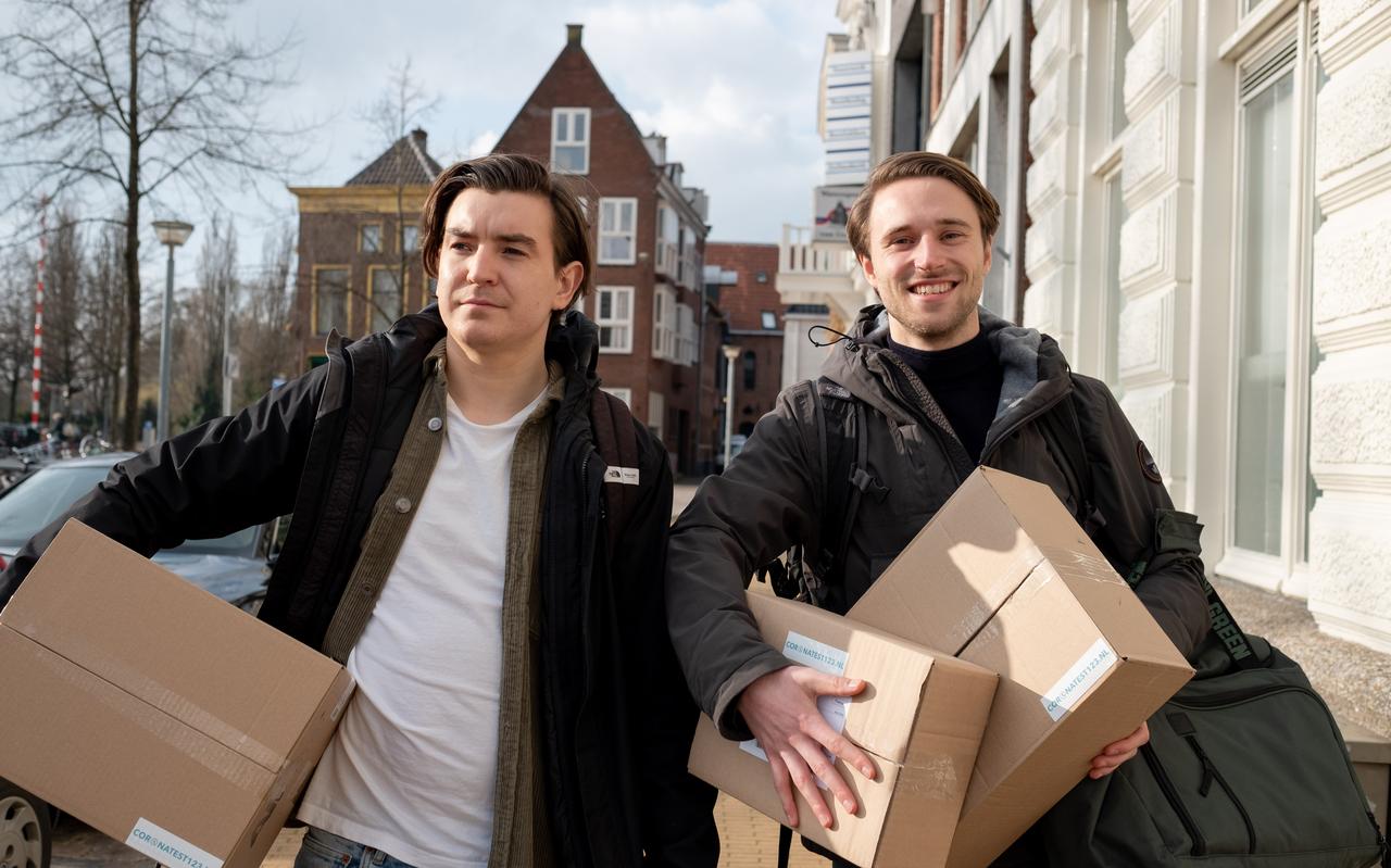 Daan Deelstra (r) en Mark Dijkhuizen sjouwen dozen coronatesten hun studentenwoningen aan de Hoge der Aa in Groningen in. Daan Deelstra (r) en Mark Dijkhuizen sjouwen dozen coronatesten hun studentenwoningen aan de Hoge der Aa in Groningen in.
