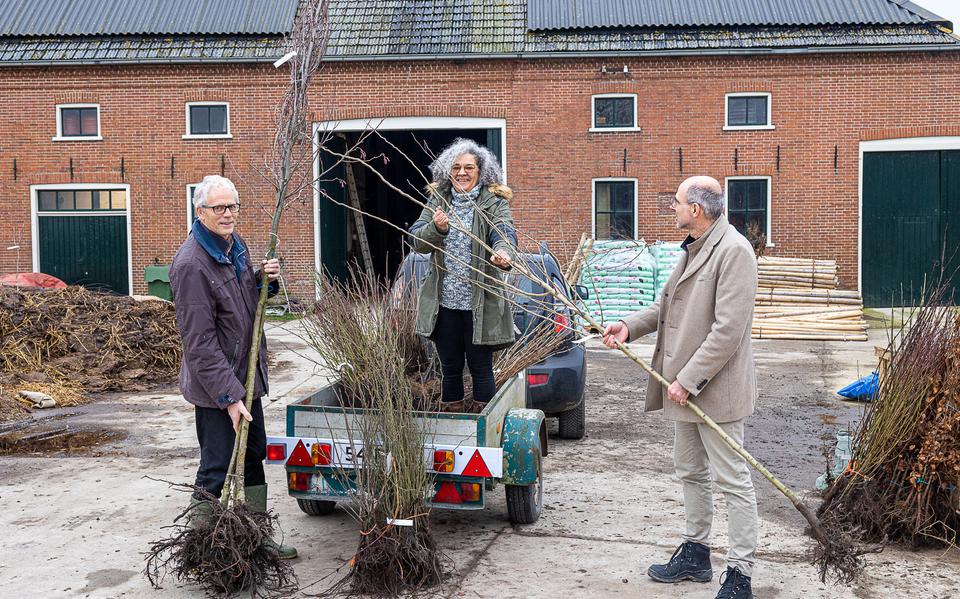 De wethouders Pier Prins (links) en Arjen Nolles helpen met het inladen van bomen en struiken voor het groene erf van Geraldine Gambier.  