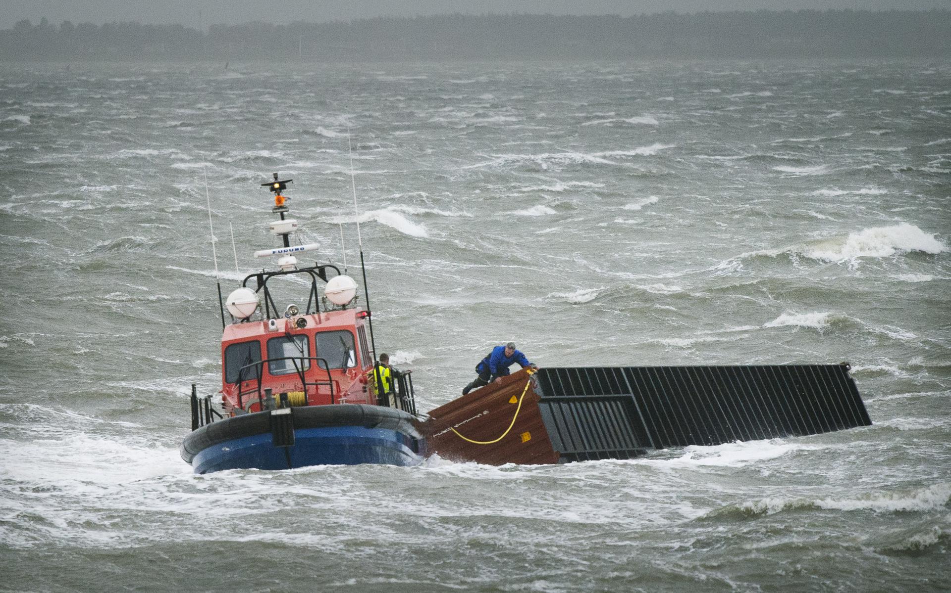 Een sleepboot sleept een zeecontainer van het schip de MSC Zoë.  