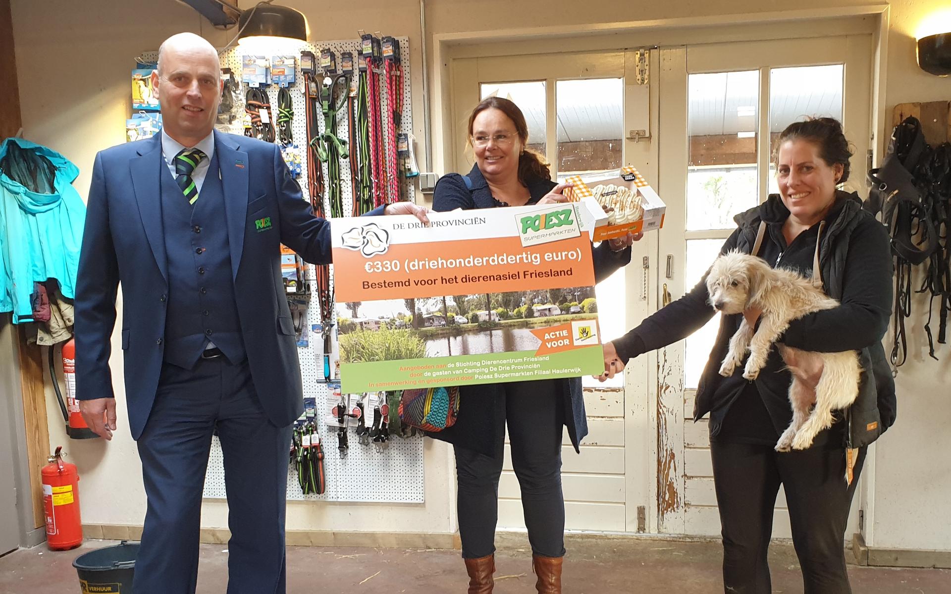 Het overhandigen van de cheque van €330 door Sjoerd (manager Poiesz Haulerwijk) en Brigitte (campinguitbater De Drie Provinciën) aan Diny (Stichting Dierencentrum Friesland).